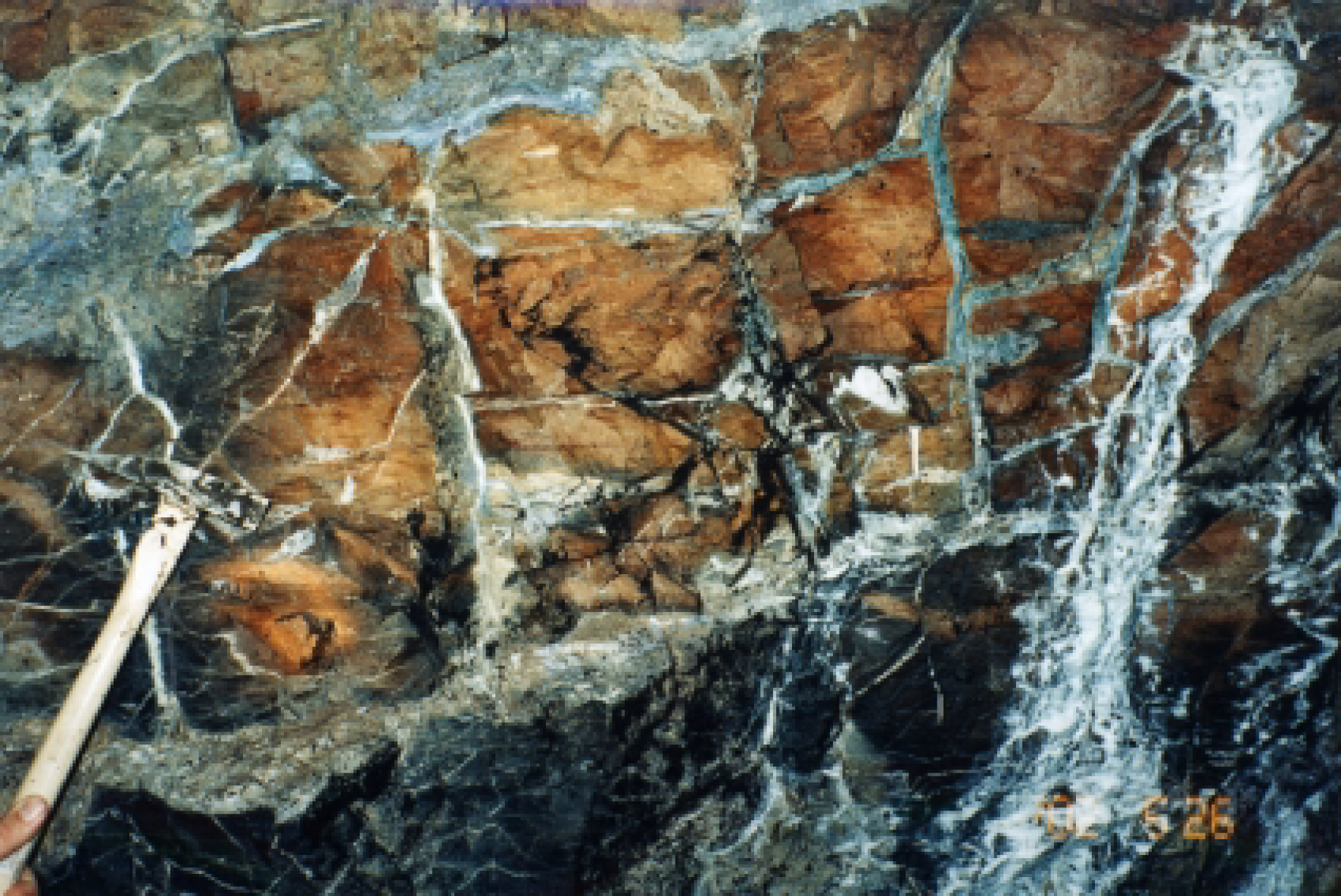 Heavily fractured micrite host rock with abundant sealed fractures containing a comparable product to natural concretes at the Maqarin site, Jordan  For scale, see hammer in bottom left corner (Pitty & Alexander 2011).